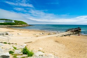 Bowleaze Cove beach - sandy rugged Dorset beach on a sunny day with low grass covered bank in the distance