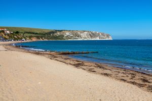 Swanage Beach - cliff backed beach with large expanse of sand which meets a blue sea