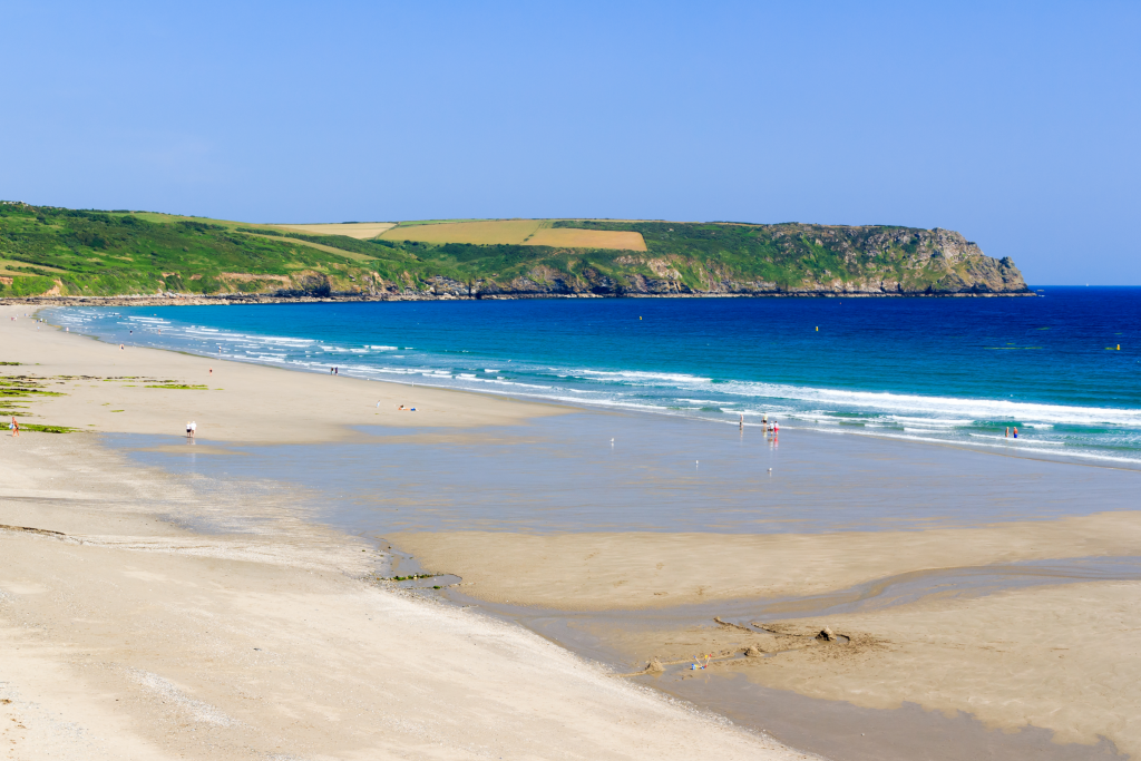 White sandy beach with turquoise ocean against backdrop of green cliffs