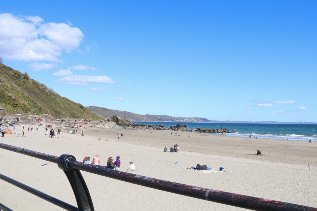 White sand beach in South Cornwall with people sunbathing on a sunny day