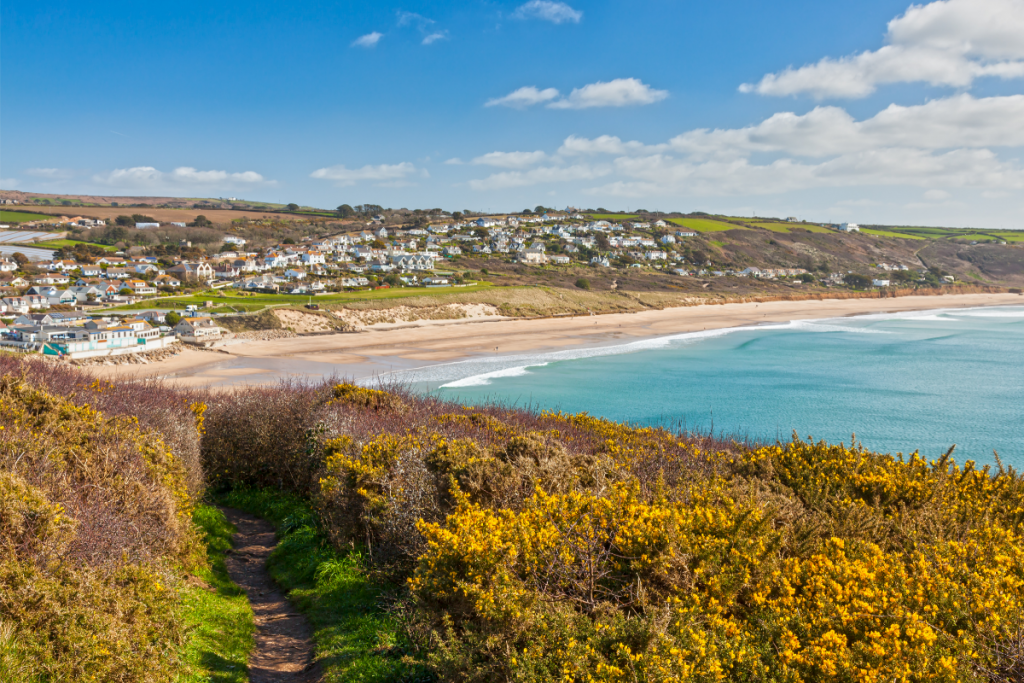 MEditerranean-like South Cornwall beach - turquoise sea lapping golden sandy coast leading to a coastal town