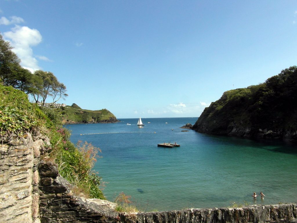 Attractive cove with deep blue sea encased with greenery against a blue sky