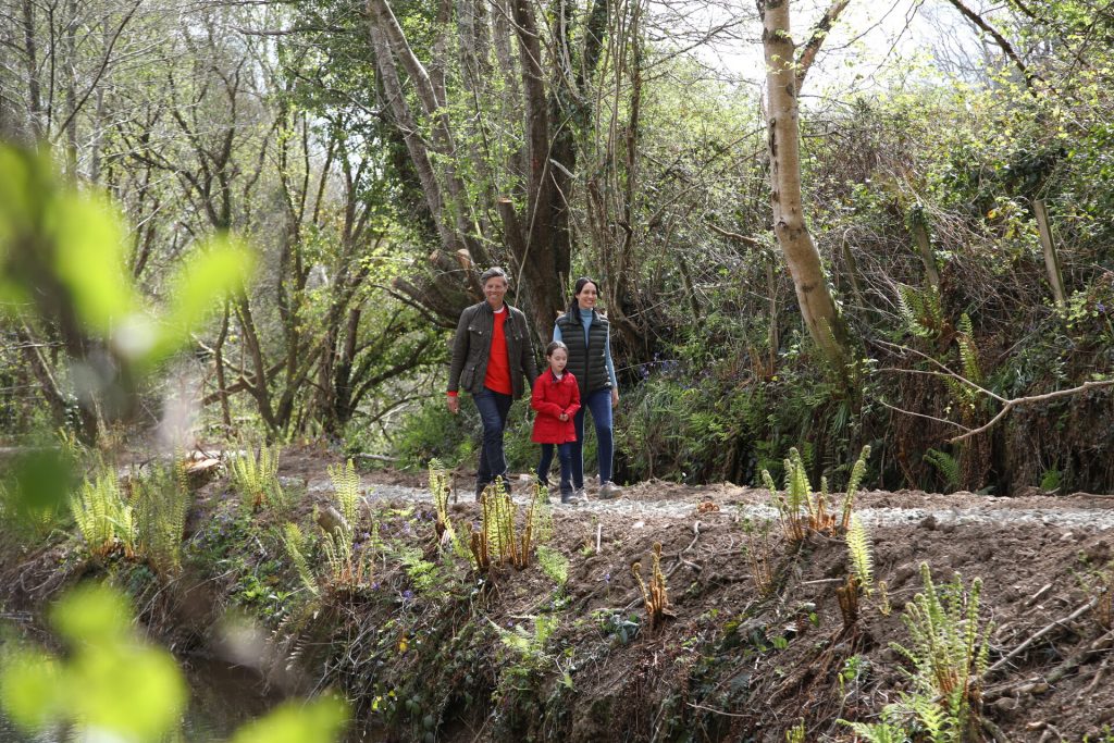 Family of three walking along a footpath in green forest surroundings