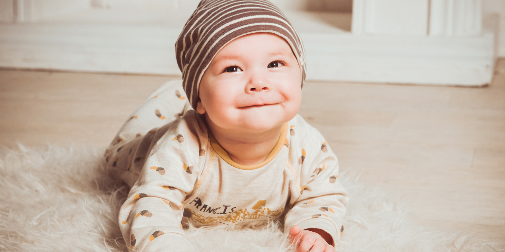 Cute baby lying on a white carpet smiling at the camera
